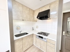 清潔感のある白タイルと木目調の収納が調和した、機能的なキッチン空間