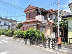 青空のもと、落ち着いた佇まいが周囲の緑と調和し、穏やかな暮らしを予感させる住まいです。