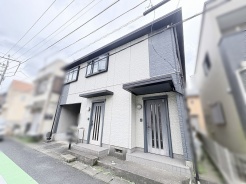 落ち着いた色合いのコントラストが洗練された印象を与える、モダンな佇まいの建物外観です。