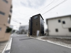落ち着いた色合いの外観が周囲の街並みに調和し、穏やかな暮らしの風景を描き出します。