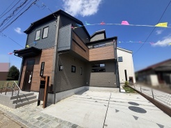 洗練された木目調の外壁が青空に映える、落ち着いた佇まいの住まい。
