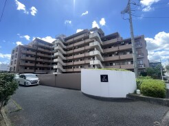 青空の下に佇む、落ち着いた色合いの重厚な外観。周辺の植栽と調和した穏やかな日常を予感させる、信頼感のある住まいです
