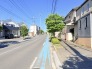 澄み渡る青空のもと、街路樹の緑が心地よいコントラストを描く、穏やかな日常の風景が広がっています
