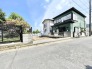 緑の家と青い空、穏やかな街並みに佇む住まい。