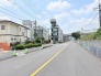 空が広く感じられる開放的な道路沿いであり、落ち着いた街並みの中で穏やかな時間が流れる周辺環境です。