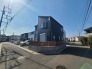 青空の下に佇む、シックな色合いの外観が周辺の街並みと調和する落ち着いた住まい。