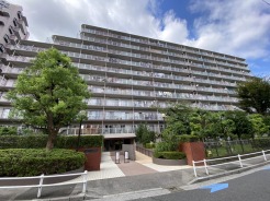 青空の下に佇む重厚な建物と豊かな緑が心地よい日常を予感させる景観