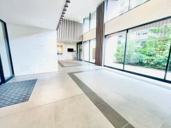 吹き抜けの高い天井と大きな窓がもたらす開放感と、外の緑の景色が調和する上品で落ち着いた空間