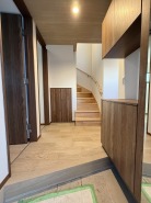 シックな色味で統一された玄関ホール室内。
コの字型の下足入れは、鍵や写真なども置ける使い勝手のいいタイプ