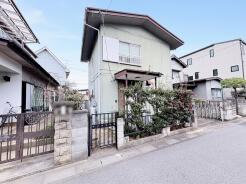 緑豊かな植栽と石積みの門が、穏やかな佇まいを演出する住まい