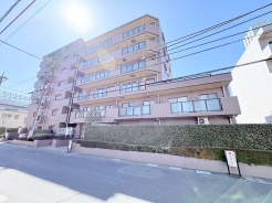 青空の下、穏やかな陽光が注ぐ、落ち着いた佇まいの住まい。