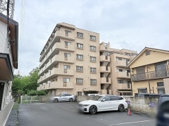 周囲の景観と穏やかに調和し、落ち着いた佇まいを見せる集合住宅の外観です。