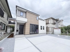 木目調のアクセントと端正なシルエットが街並みに静かに調和する、洗練された佇まいの住まい。