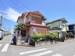 青い空に映える淡い外壁と豊かな緑が、穏やかな街並みの中で心地よい調和を感じさせる佇まいです。