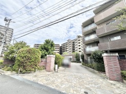 緑豊かな植栽と重厚感のある門構えが調和する、落ち着いた佇まいのアプローチ。