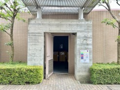 緑豊かな植栽とコンクリートの質感が調和する、落ち着いた佇まいのエントランスアプローチ。