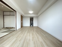 温かな木目調の床が心地よい広がりを感じさせ、ふすま戸の向こうには和の趣も感じられる、穏やかで落ち着いた住まい。